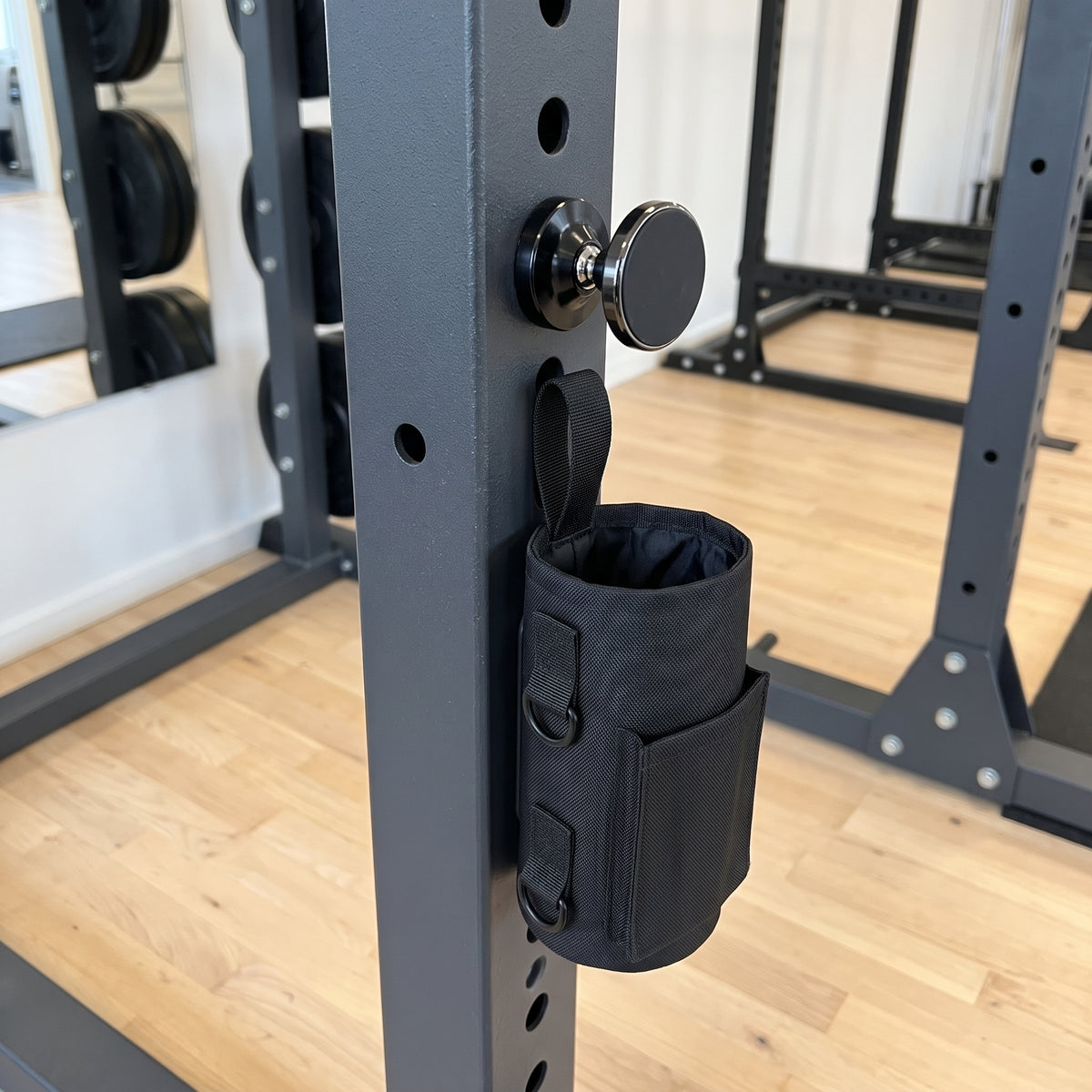 Gympaketet: svart magnetisk gymväska och svart magnetisk mobilhållare fästa på stålramen i ett gym