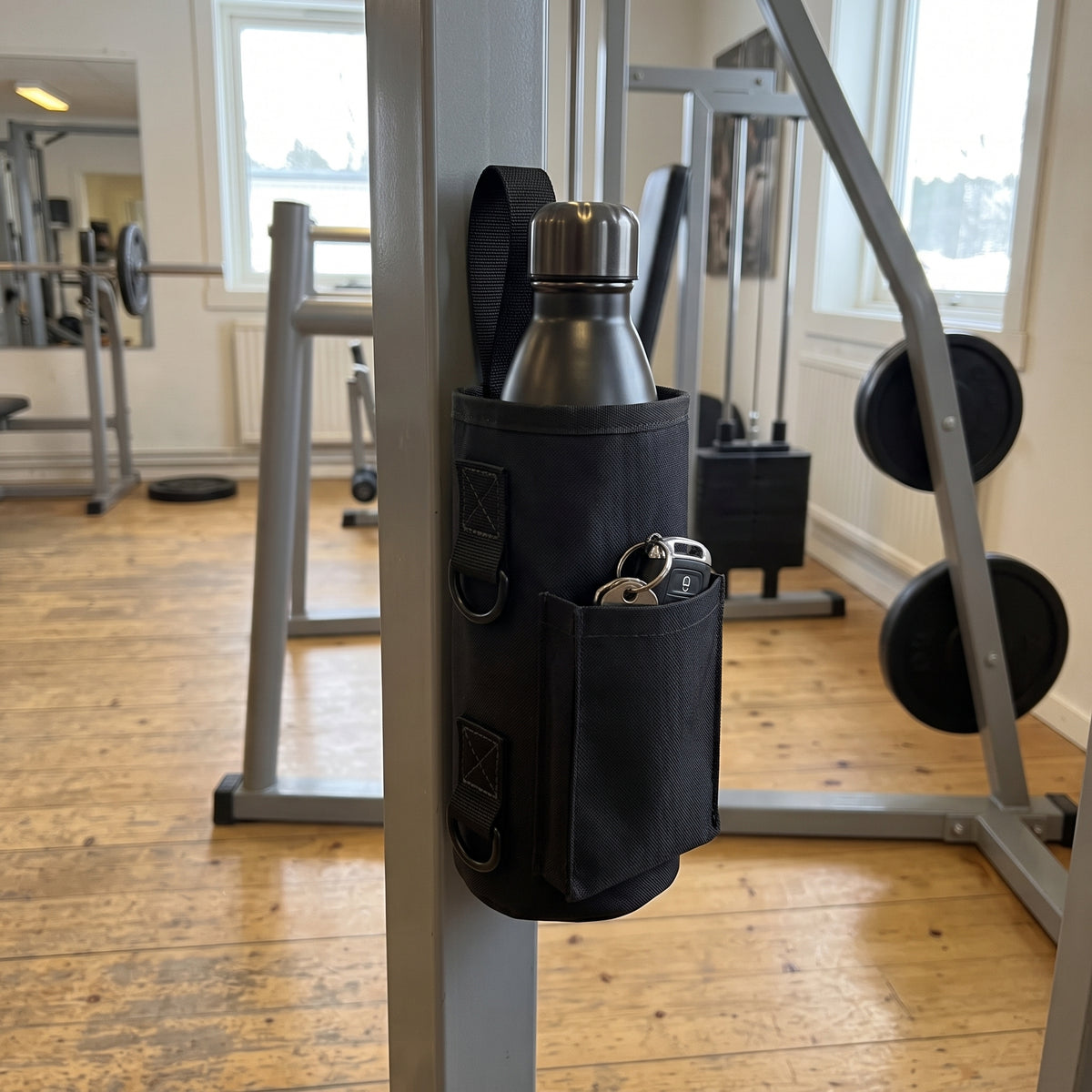 Svart magnetisk gymväska fäst på stålramen av en träningsmaskin i ett svenskt gym