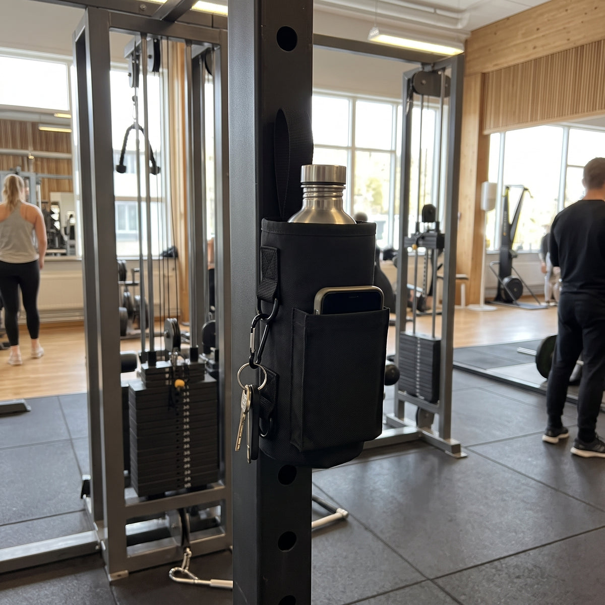 Svart gymväska på maskin med vattenflaska och mobil i fickorna