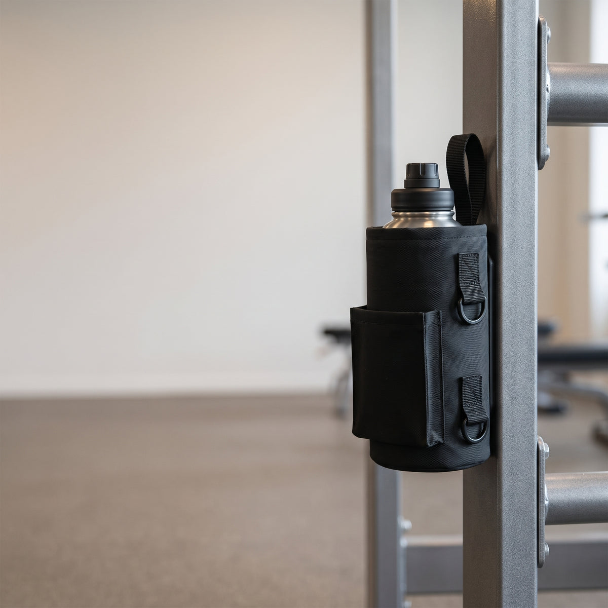 Svart magnetisk gymväska fäst på en träningsmaskins stålram med fri yta till vänster för fördelar
