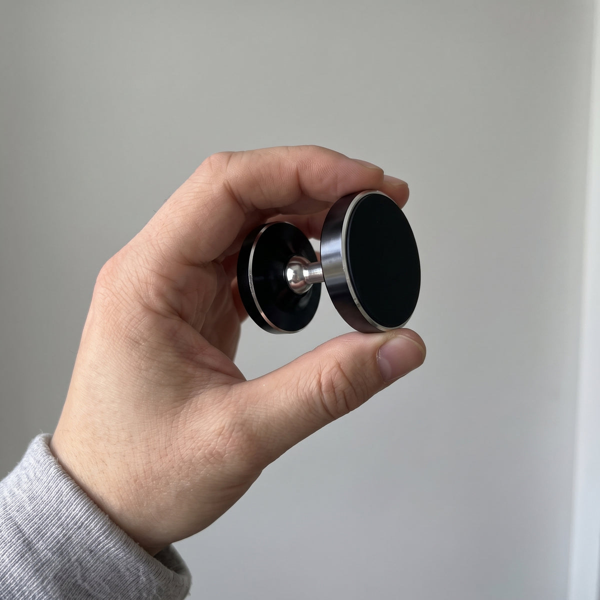 Den svarta magnetiska mobilhållaren i en hand, så att du ser storleken