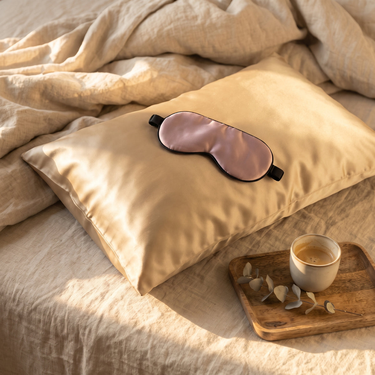 Sömnsetet i gyllene morgonljus: silkesörngott i guld och mauve sovmask på en ombonad säng